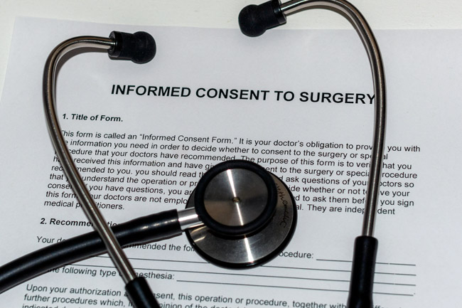 A physician's stethoscope on top of a blank form that's titled informed consent to surgery