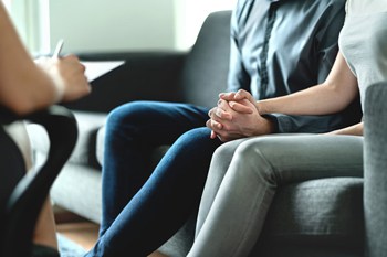Visual link to the personal injury and wrongful death practice area page showing a couple sitting on a sofa and discussing their case with a lawyer
