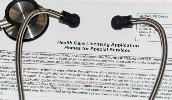 A physicians stethoscope on top of a form that's titled healthcare licensing application homes for special services
