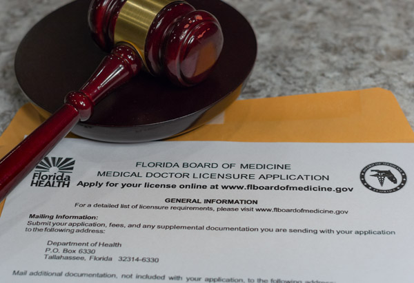A gavel on top of a Florida Board of Medicine Medical Doctor Licensure Application
