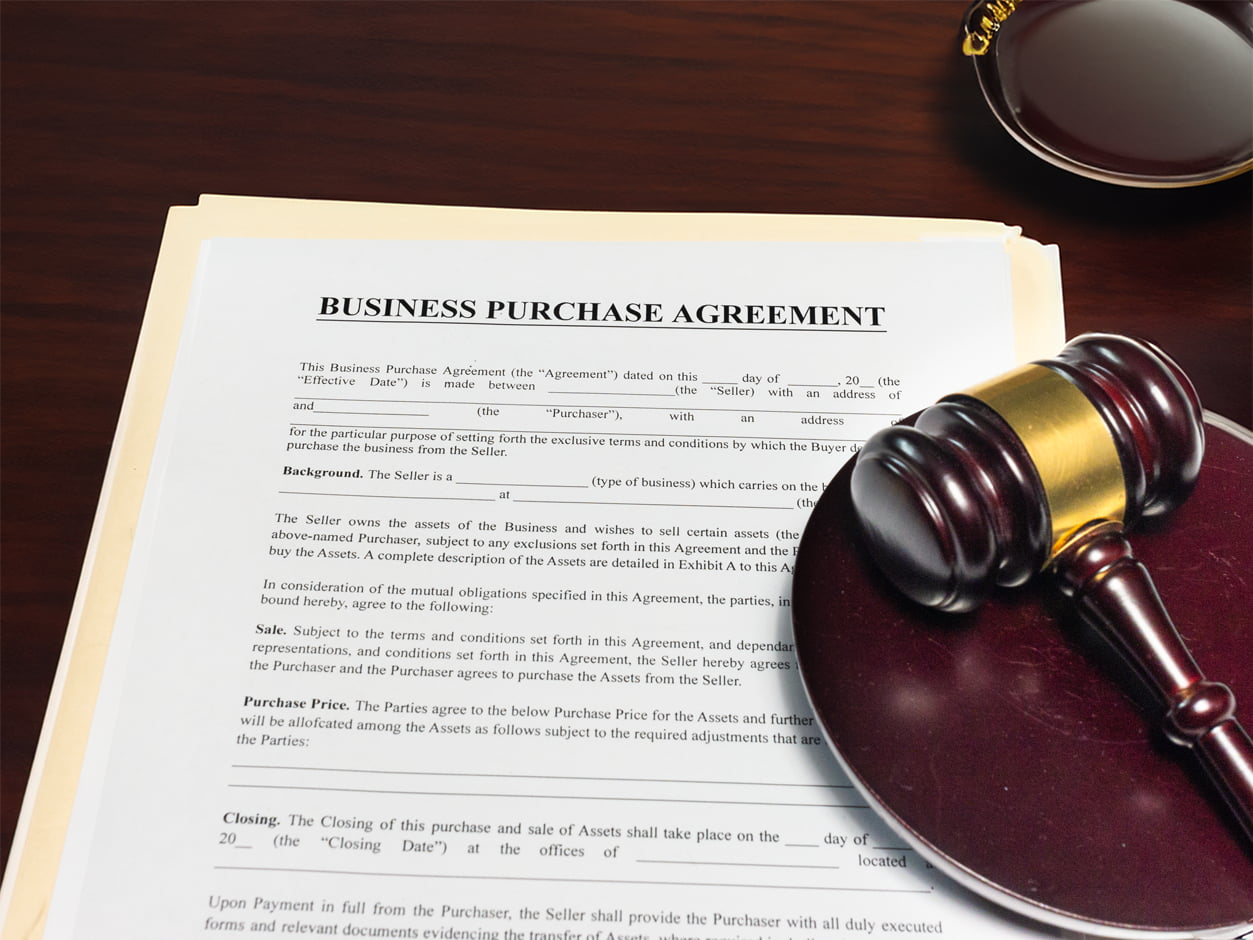 Blank copy of a business purchase agreement for healthcare practices next to a judges gavel