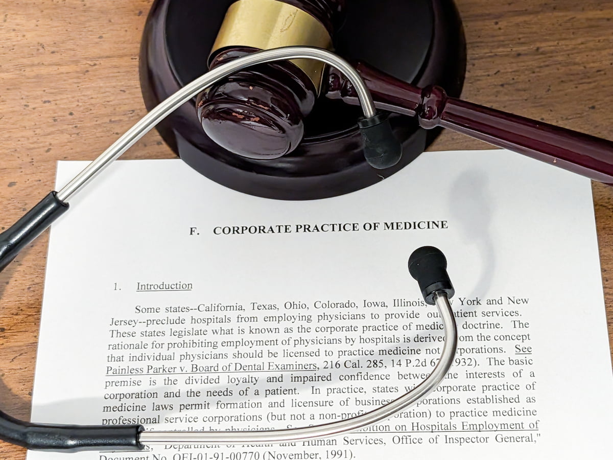 Stethoscope and judge’s gavel resting on a legal paper titled “Corporate Practice of Medicine,” referencing state laws on non-physician ownership of medical practices.