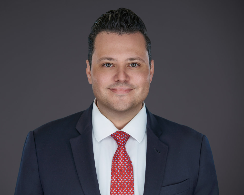Professional headshot of Rudy Mayor wearing a navy suit and red tie, Florida estate litigation lawyer at Di Pietro Partners