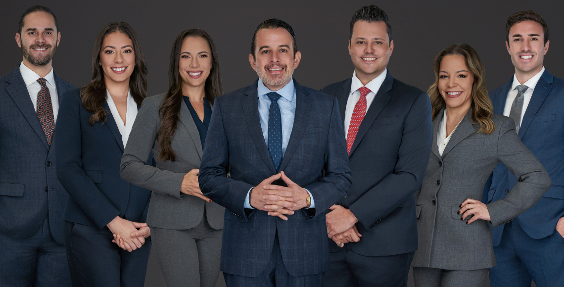 Group photo of seven attorneys from Di Pietro Partners standing in business suits against a dark background, Florida healthcare and probate litigation law firm