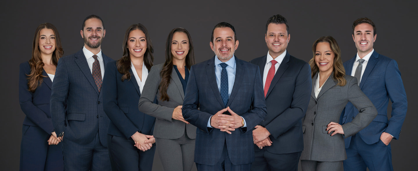 Group photo of eight attorneys from Di Pietro Partners standing in business suits against a dark background, Florida healthcare and probate litigation law firm